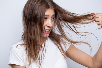 Young woman applying natural organic essential oil on hair