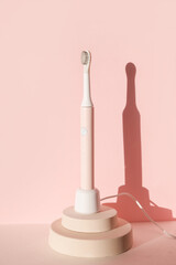 New modern ultrasonic toothbrush. Dental care supplies on cylinder podium on pink pastel background. Oral hygiene, dental and gum health, healthy teeth. Dental products 