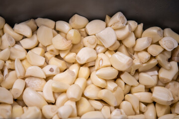 Pile of cleaned garlic in aluminium bowl. Natural background.