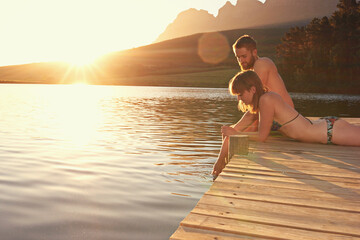 Its been a perfect day in paradise. Shot of an affectionate young couple in swimsuits sitting on a...