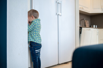 Boy playing hide and sick in the kitchen