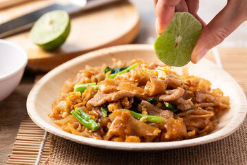 Thai food (Pad See Ew), Stir fried rice noodles with soy sauce, egg, kale and pork eating with lime