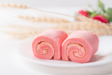 Pink strawberry roll cake or swiss roll with whipped cream and strawberry flavor on white background