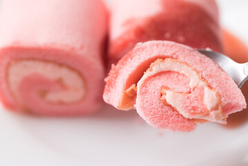 Pink strawberry roll cake or swiss roll with whipped cream and strawberry flavor eating by spoon
