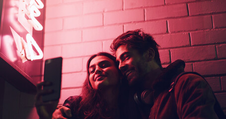 This is a night to remember. Shot of a young couple taking a selfie while standing outside a building at night.