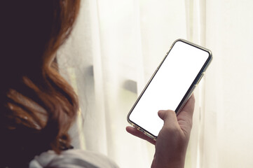 Close up women using a smartphone with an empty white screen at home with window light.