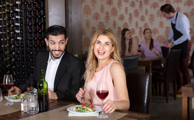 Loving happy cheerful positive pair enjoying evening meal and conversation in cozy restaurant