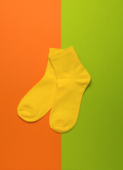 Sports yellow socks on a green and orange background. Flat lay.