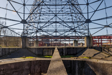 Low angle and selective focus view inside former gasometer, existing structure against blue sky. 