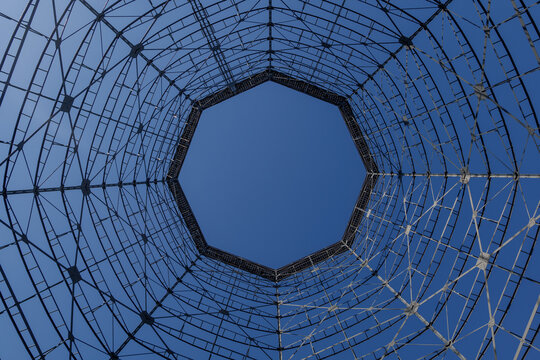 Uprisen angle view inside former gasometer, existing structure against blue sky. 