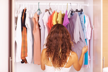 Woman going through her clothes. Rear view of a woman going through the clothes in her closet.