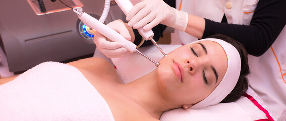 Naklejka premium Woman getting facial mask, beauty treatment and skincare in modern beauty spa.