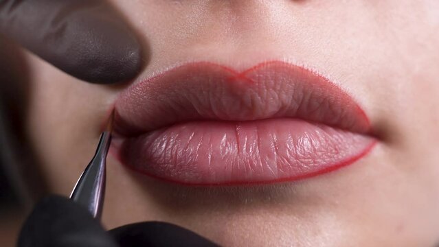 procedure of permanent lip tattooing, the master applies a contour to the lips of the model before applying the tattoo.