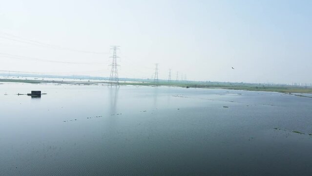 Aerial drone shot of the agricultural land covered in water due to heavy rain, high voltage electric towers in the agricultural fields.