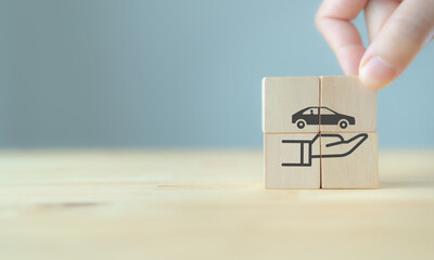 Car (automobile) insurance and collision damage waiver concepts. Hand holds the wooden cubes with care protection symbol on  grey background and copy space. Car insurance and business banner.