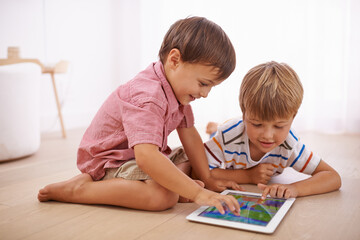 Showing him some tablet tricks. Shot of little boys playing on the floor.