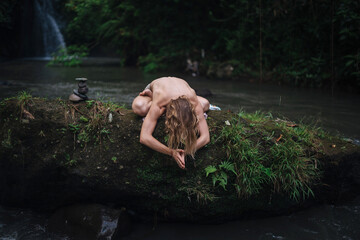 Yoga practice and meditation in nature. Man practicing near river