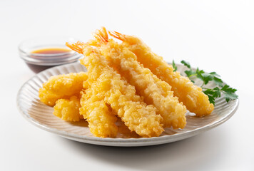 Shrimp tempura on a plate placed on a white background.
