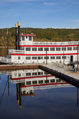 Obraz premium Old fashioned river boat docked on a calm river in fall