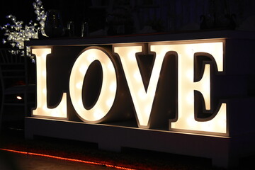 Letrero de luces con la palabra LOVE ocupado en eventos sociales - obrazy, fototapety, plakaty