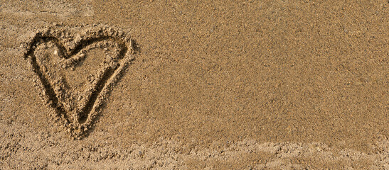 The heart symbol is written on wet sand