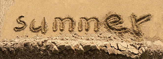 Inscription summer in letters on the wet yellow sand