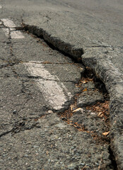 Fototapeta na wymiar Deep cracks in the road, hole in the pavement of the highway