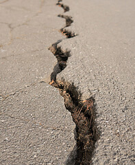 Deep and long crack with debris on an old highway.