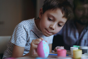 Fototapeta na wymiar Cute little boy colouring eggs for easter