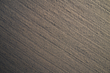 Brown plowed field. Brown background on the field aerial view. Earth top view. Aerial image of rows of plowing lines. texture plowed, cultivated land. can be used as a background.