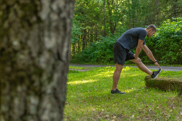 A young enduring athletic athlete is doing stretching in the forest outdoors, around the forest, oak trees.healthy athlete nature, lifestyle trail athletic person marathon, park outside. Autumn body