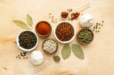 Different types of peppers in small bowls on wooden background, top view