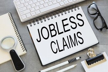Fototapeta premium open notebook on a gray background near stationery. text in notepad. jobless claims. Business concept.