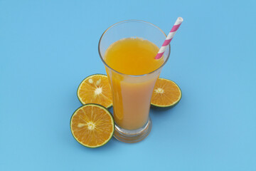 Orange juice with drink straw and orange fruits on blue background