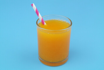 Orange juice with drink straw on blue background