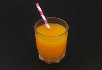 Glass of fresh orange juice with drink straw on black background	
