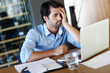 I dont think Im going to meet the deadline. A frustrated employee sitting at his desk and working on his laptop.