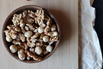 A mixture of nuts in a wooden bowl on a wooden board. Dried nuts.