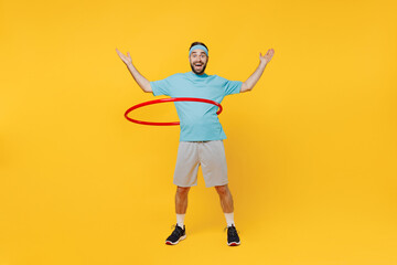 Full size young fitness trainer instructor sporty man sportsman in headband blue t-shirt spend weekend in home gym man use hula hup isolated on plain yellow background Workout sport motivation concept © ViDi Studio