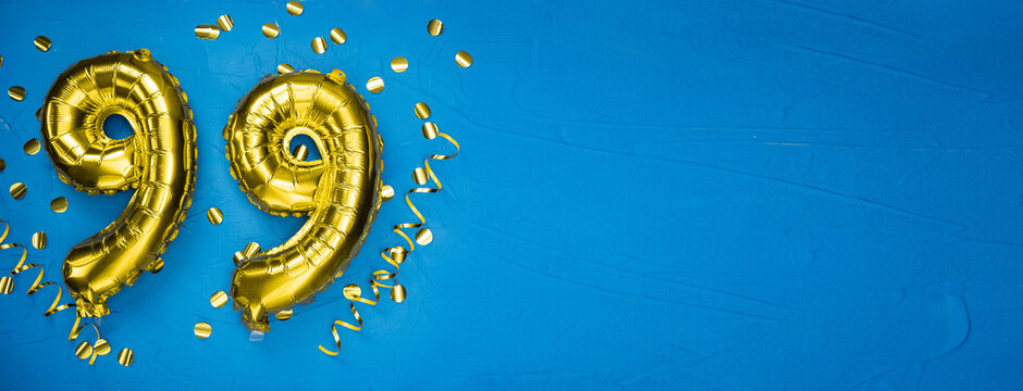 golden yellow foil balloon on blue concrete background number ninety nine. Birthday or anniversary card with 99 inscription. Anniversary celebration. .