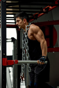Pain during exercise, work with his own weight, the athlete does exercises on the uneven bars overcoming pain with a chain around his neck
