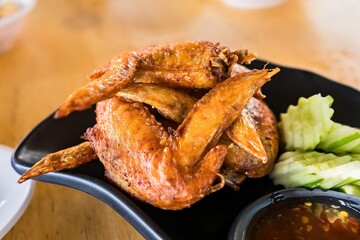 Deep fried chicken wings and green fried herb leaves, selective focus of Thai meal.