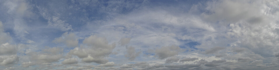Panorama of a blue cloudy sky completely covered with gray clouds