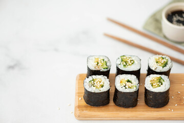 vegetable sushi with cucumber and sesame seeds on a wooden board