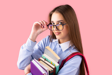 Pretty girl teen student with backpack holds books touching glasses with fingers having smart facial expression, education in high school concept.