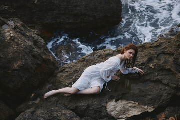 Barefoot woman lying on her back on a rocky seashore unaltered