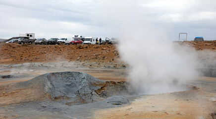 Fototapeta na wymiar Hverir, Iceland on august 1, 2021: Parking near a steaming fumarole in geothermal area of Hverir, Iceland