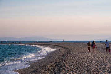 Beautiful view of iconic Posidi sandy beach, paradise cape and Peninsula in Kassandra, Halkidiki, North Greece. People walking, swimming and sunbathing on sea beach.