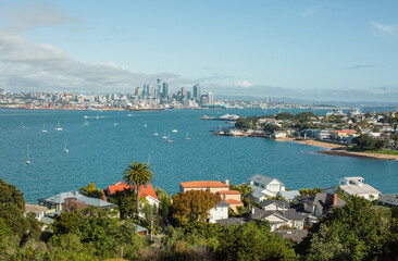 Auckland city line as seen from Devonport, North Head Historic Reserve. Sunny day, yachts on the water, roofs in the foreground.