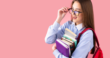 Side view photo of a school teenage girl in uniform with backpack and books giving a wink pushing back glasses, college concept.